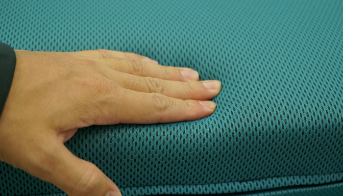 Hand of a man inspecting a green cushion